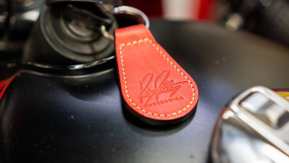 Red Ray Petty Meccanica key fob with stitched edges on a fuel tank
