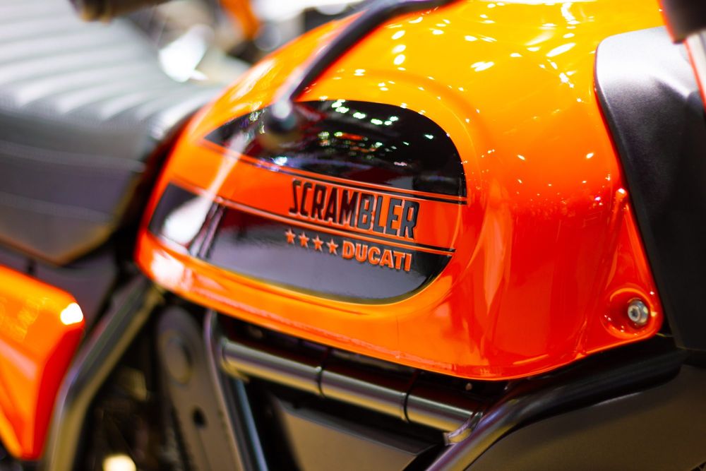 Orange fuel tank of a Ducati Scrambler, with the Scrambler badge