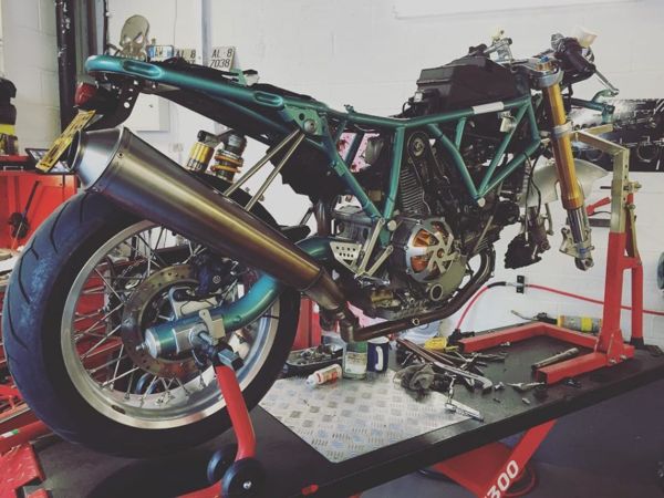 Classic Ducati with green trellis frame being rebuilt on a lift