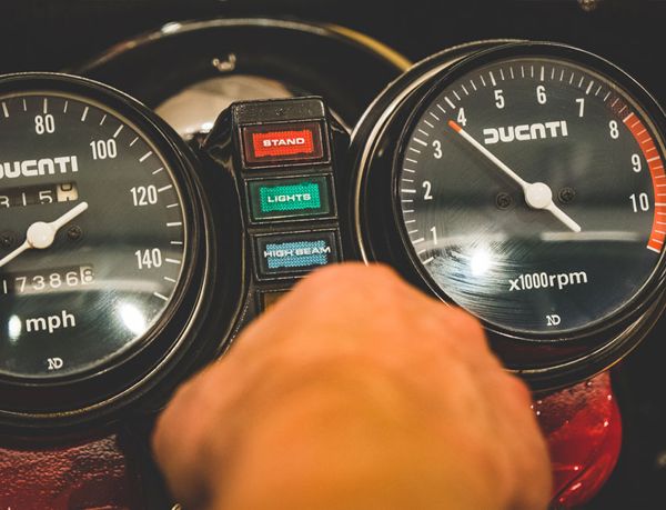Hand on the clocks of a classic Ducati, beside its warning lights