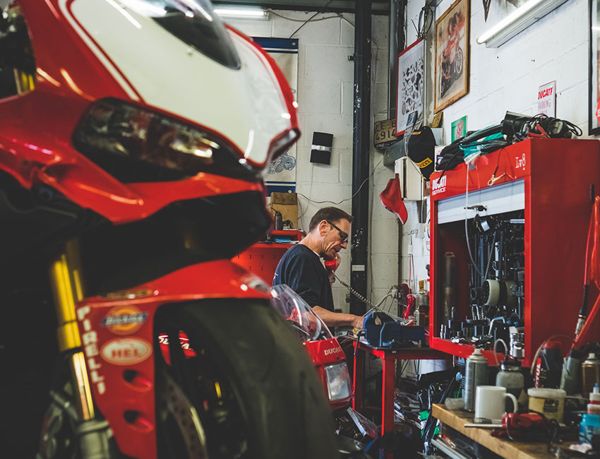 Ducati Panigale on a lift with a mechanic at the workbench