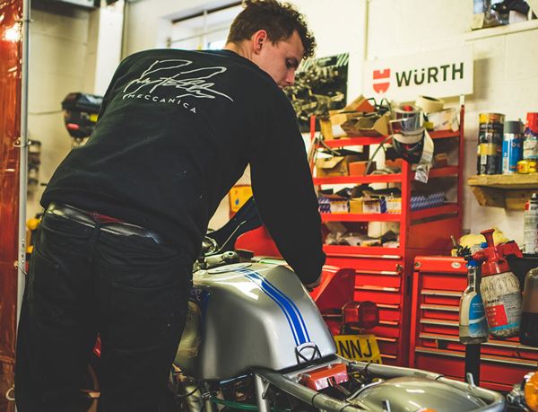 Mechanic in an RPM sweatshirt working on a silver and blue Ducati 900SS