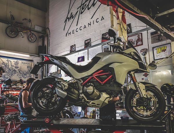 Ducati Multistrada on a lift under the Ray Petty Meccanica sign