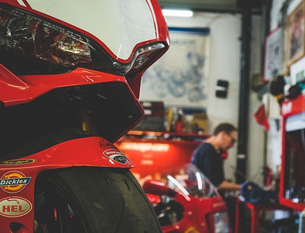 Front of a red Ducati superbike with a mechanic working behind