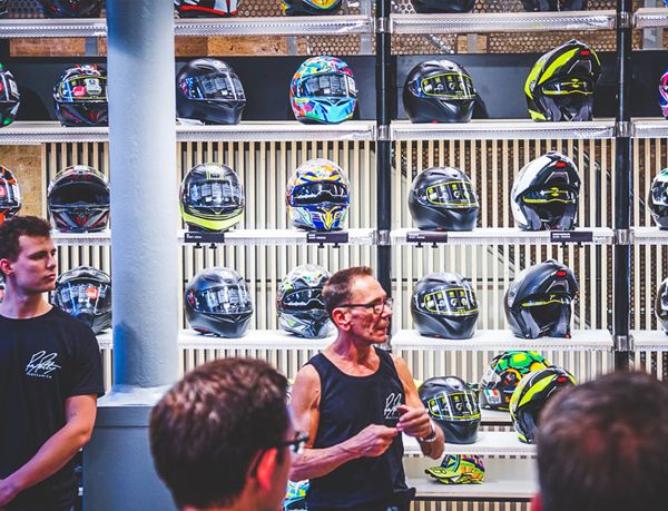 RPM team member speaking to guests in front of a wall of helmets