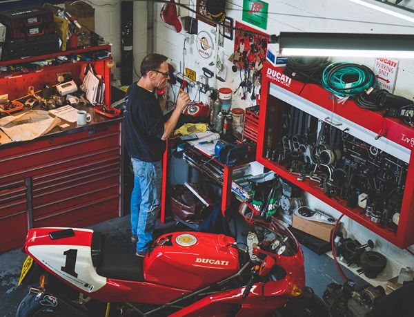 Mechanic at the workbench behind a red Ducati with a white number 1 tail