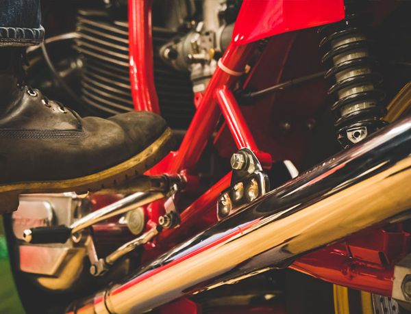 Rider's boot on the footpeg beside the Ducati's chrome exhaust