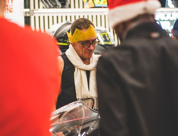 Guest in a paper crown beside a classic Ducati's screen