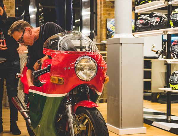 Mechanic checking a classic red and green Ducati with a round headlight