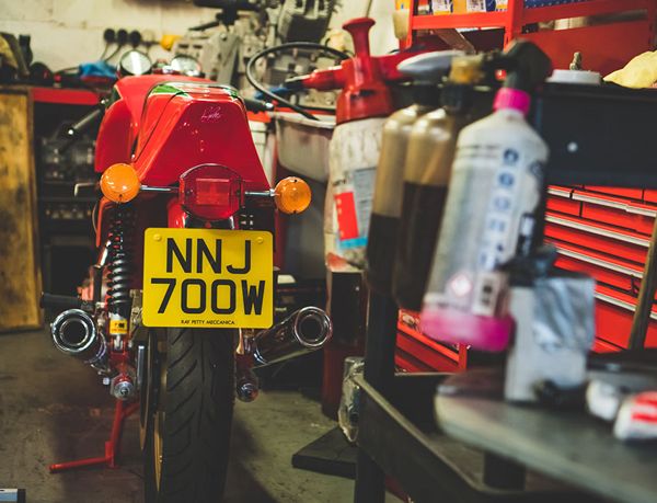 Rear of a red classic Ducati with a yellow number plate, on a stand