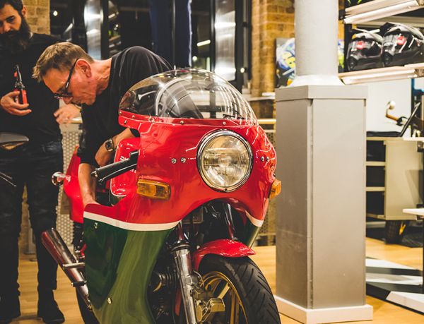 Mechanic checking a classic Ducati with a round headlight in the store