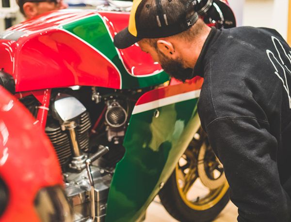 Mechanic in a cap looking over a classic Ducati's engine