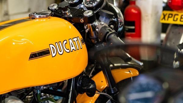 Yellow Ducati fuel tank with a black pinstripe in the workshop