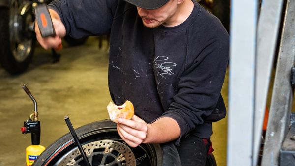 Mechanic in an RPM sweatshirt taking a break beside a wheel