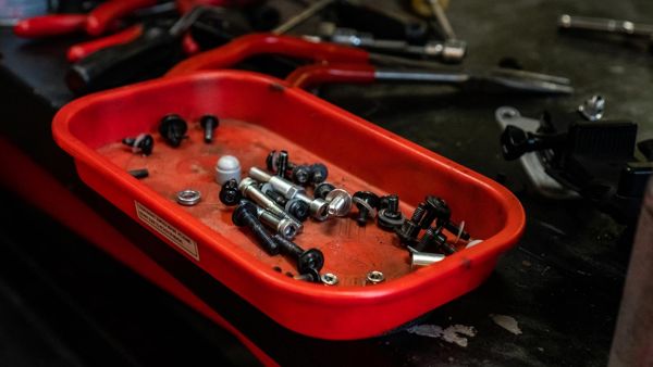 Red parts tray full of bolts on the workbench