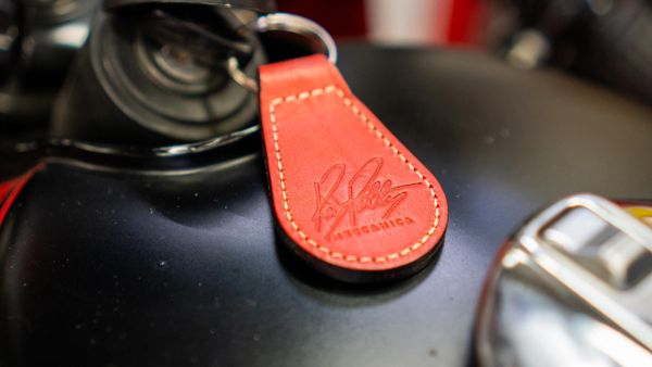 Red leather Ray Petty Meccanica key fob on a black fuel tank
