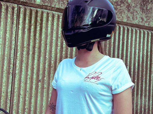 Woman wearing the white Ray Petty Meccanica T-shirt and a full-face helmet