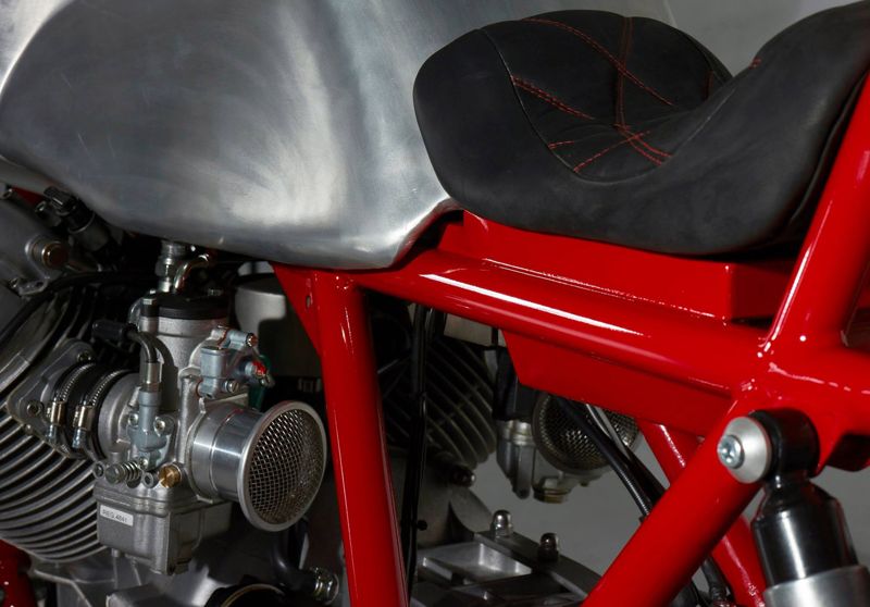 Carburettor, red frame and black seat of the custom Moto Guzzi