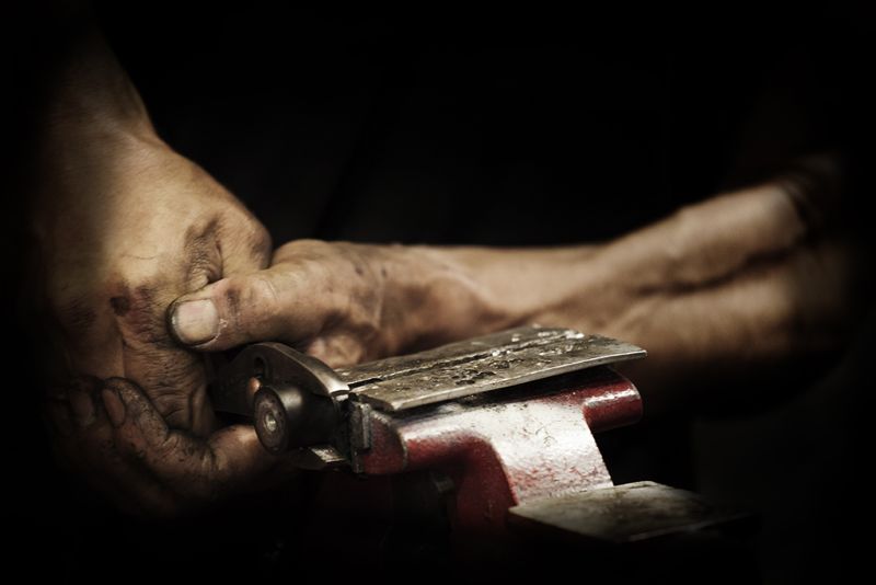 Ray Petty's hands holding a part in a bench vice